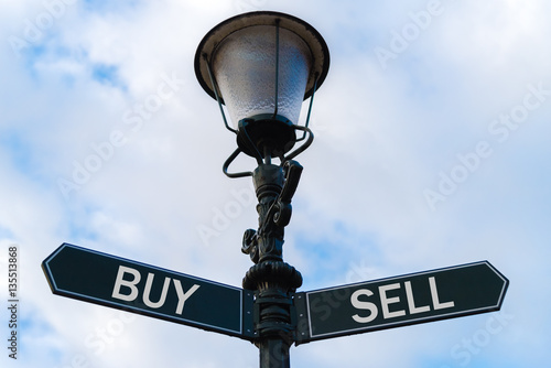 Buy versus Sell directional signs on guidepost