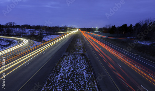Multi-lane highway during rush hour winter commute, light trails