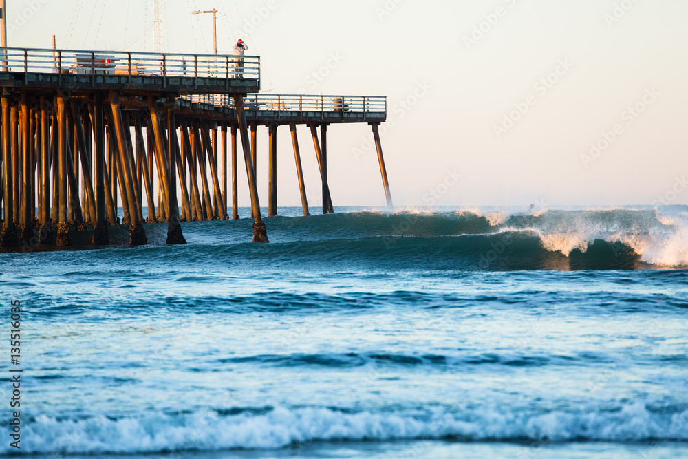 Surfer on wave at dawn under the Pismo Beach pier