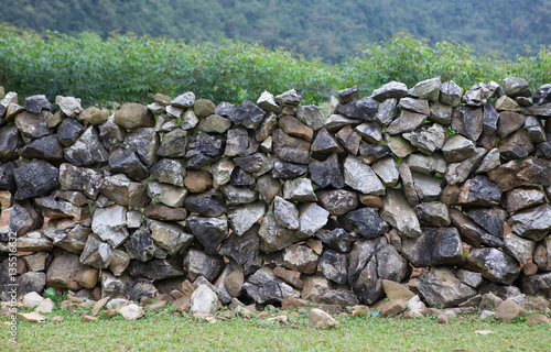 Stone wall on a hill with grass field