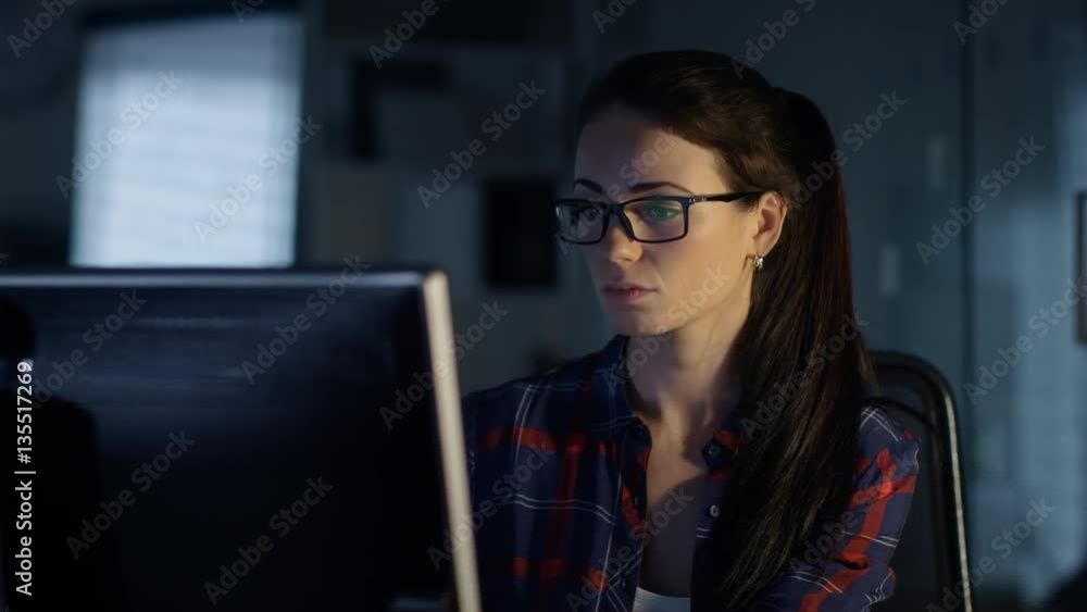 Late at Night in the Office Woman in Glasses Sits at Her Desk and Works on Personal Computer. Rest of the Room is Illuminated by Moonlight. Shot on RED Cinema Camera 4K (UHD). Late at Night in the Office Woman in Glasses Sits at Her Desk and Works on Personal Computer. Rest of the Room is Illuminated by Moonlight. Shot on RED Cinema Camera 4K (UHD).