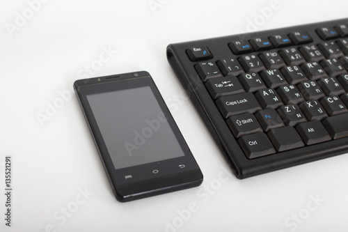 Computer keyboards and smart phone on a white background.