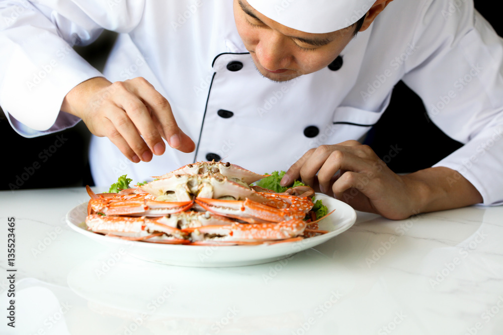 Asian chef preparing and decorating grilled crab seafood meal with vegetable