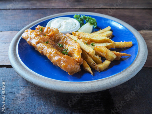 Fish and chip in blue plate on wood table 