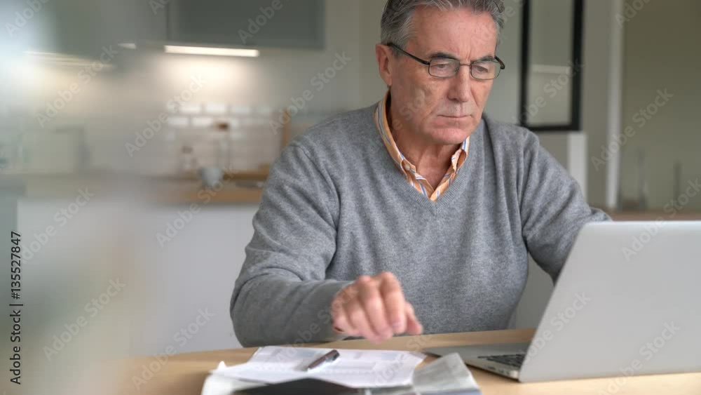 Senior man at home connected on laptop computer Senior man at home connected on laptop computer