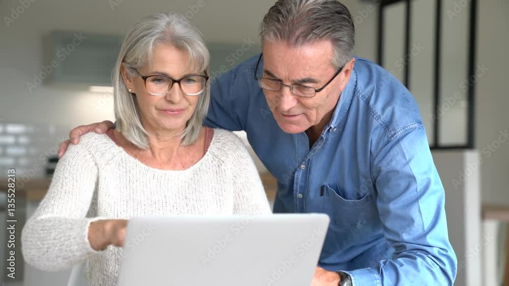Senior couple at home using laptop computer Senior couple at home using laptop computer