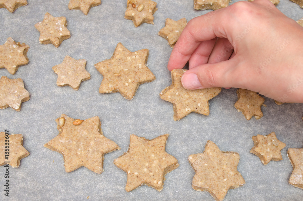 female hand take cutted Christmas cookies from rye dough with star shaped cutter