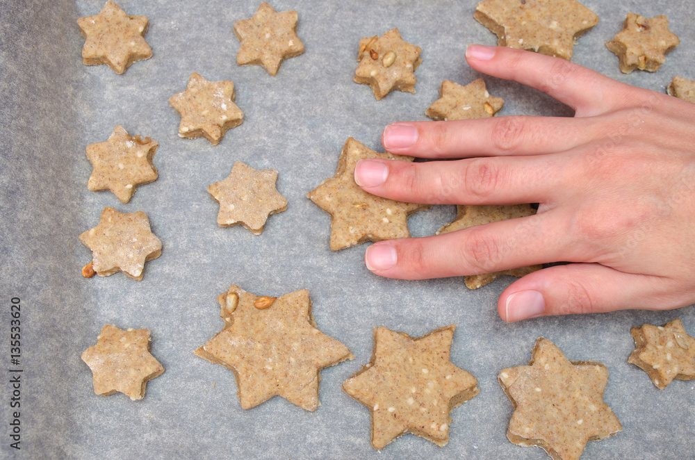 female hand touch cookies made of rye dough with star shaped cutter female hand touch cookies made of rye dough with star shaped cutter