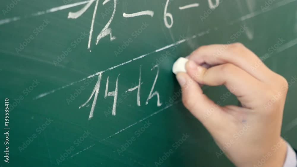A pupil`s hand writing figures on the chalkboard. Closeup. A pupil`s hand writing figures on the chalkboard. Closeup.