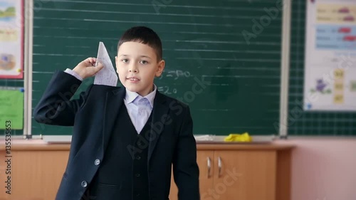 A school boy throwing paper airplane in a classroom. Slow motion. photo