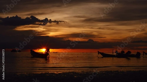 Sunrise on a tropical beach. silhouettes of boats and people, sand and sea. photo