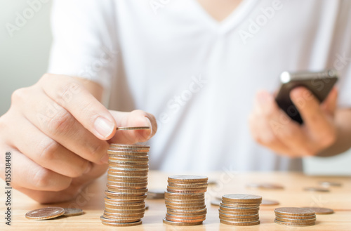 Man putting coins on stack with holding smartphone, Concept business, finance, money saving