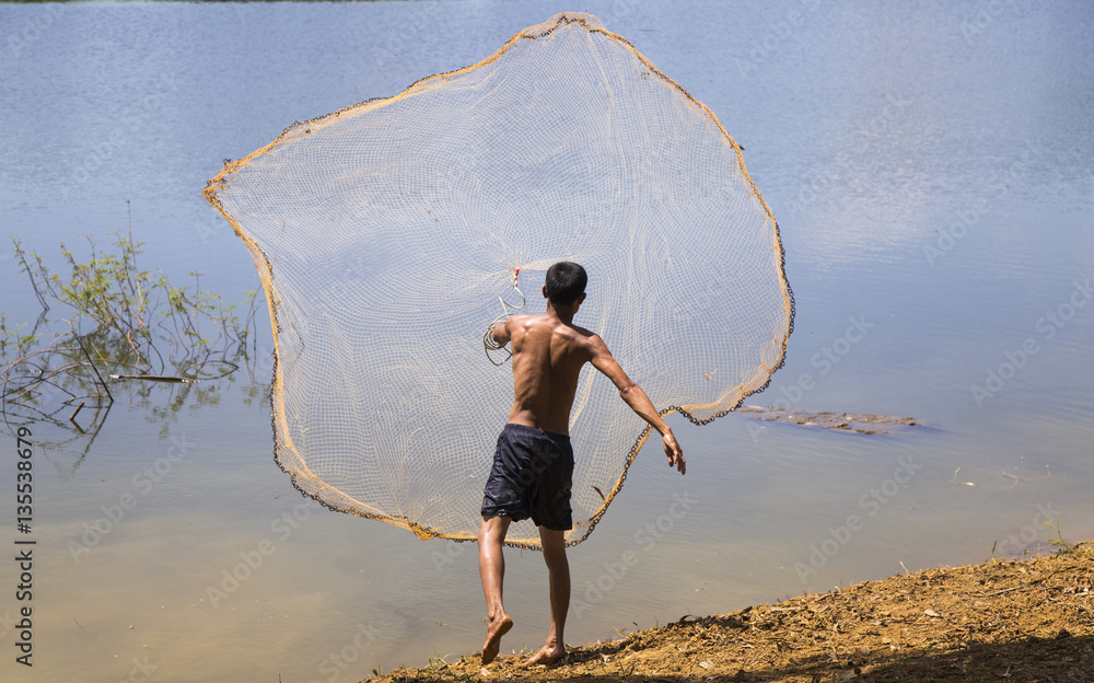 Asian fisherman throwing fishing net under the sunlight Stock Photo