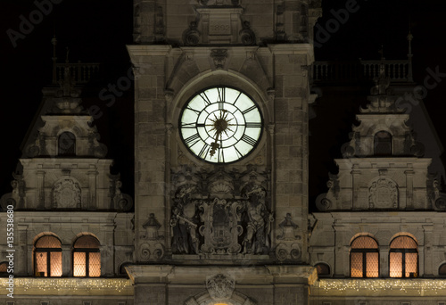 Night view of the illuminated clock on the tower of the town hall