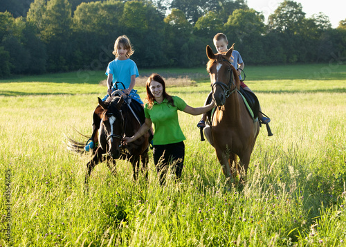 Horseback Riding Lessons - Woman Leading Two Horses with Boys