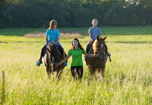 Horseback Riding Lessons - Woman Leading Two Horses with Boys © courtyardpix