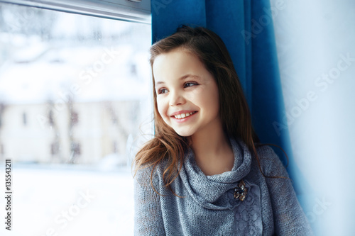 Child girl sitting on a windowsill and bunny hugs. 