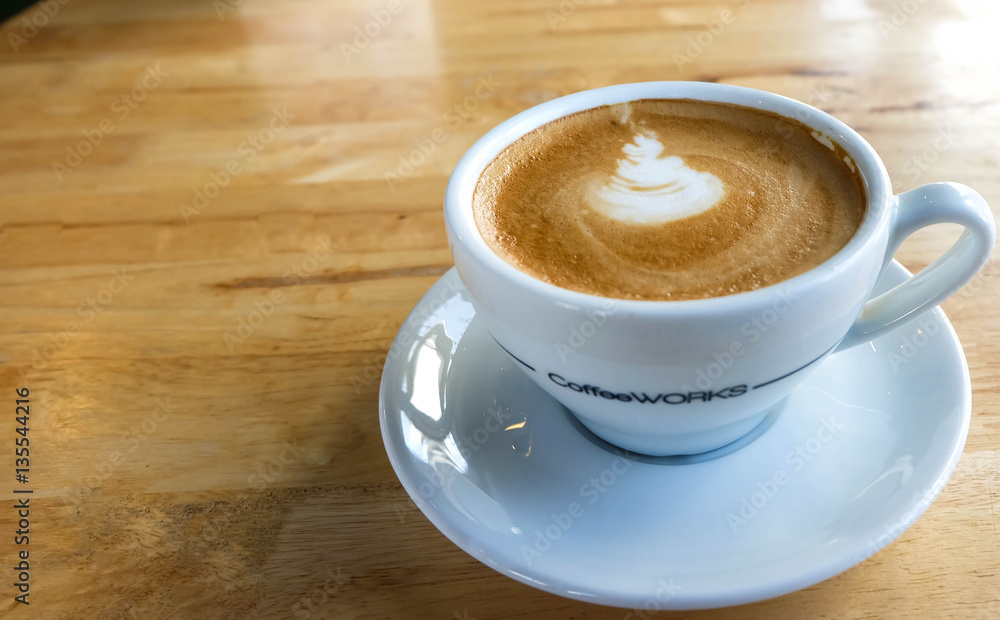 A cup of coffee with latte art in a white cup on wooden table ba A cup of coffee with latte art in a white cup on wooden table ba