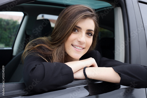 Beautiful woman with long silky hair sitting in car smiling