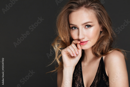 Pretty woman standing and posing over dark background.