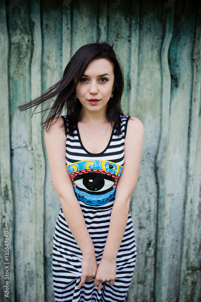 Fototapeta premium Brunette model girl at dress with stripes background cian wooden