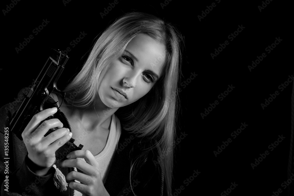 serious girl with gun on black background with copyspace, monochrome serious girl with gun on black background with copyspace, monochrome