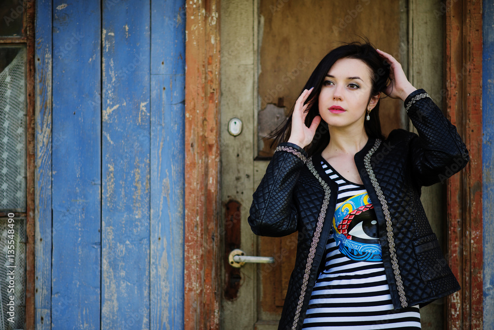 Fototapeta premium Brunette model girl at leather jacket posed background old woode