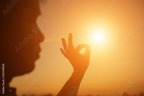 hands forming a heart shape with sunset silhouette