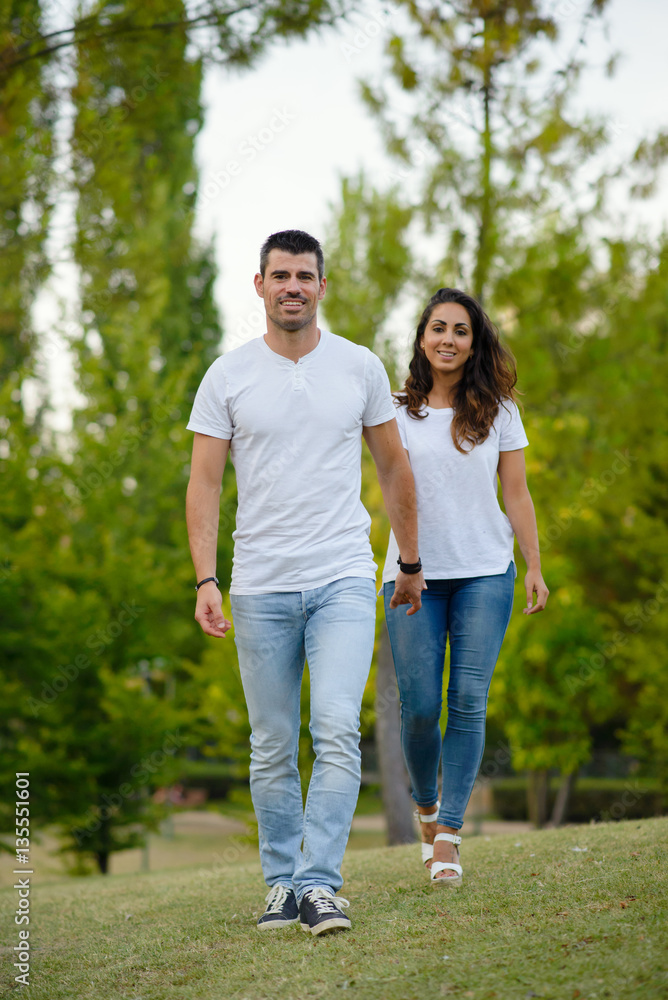 Happy young casual couple walking together in the park. Happy young casual couple walking together in the park.