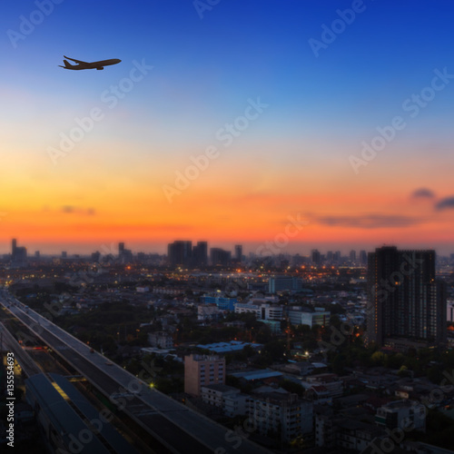 Silhouette of airplane flying in a sky over the city at sunrise