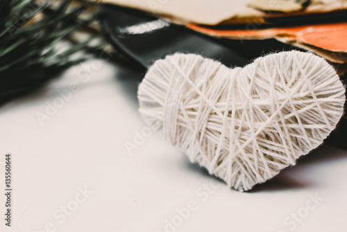 white knitted heart and stack of scratched dusty old vinyl records tied with rope on white background