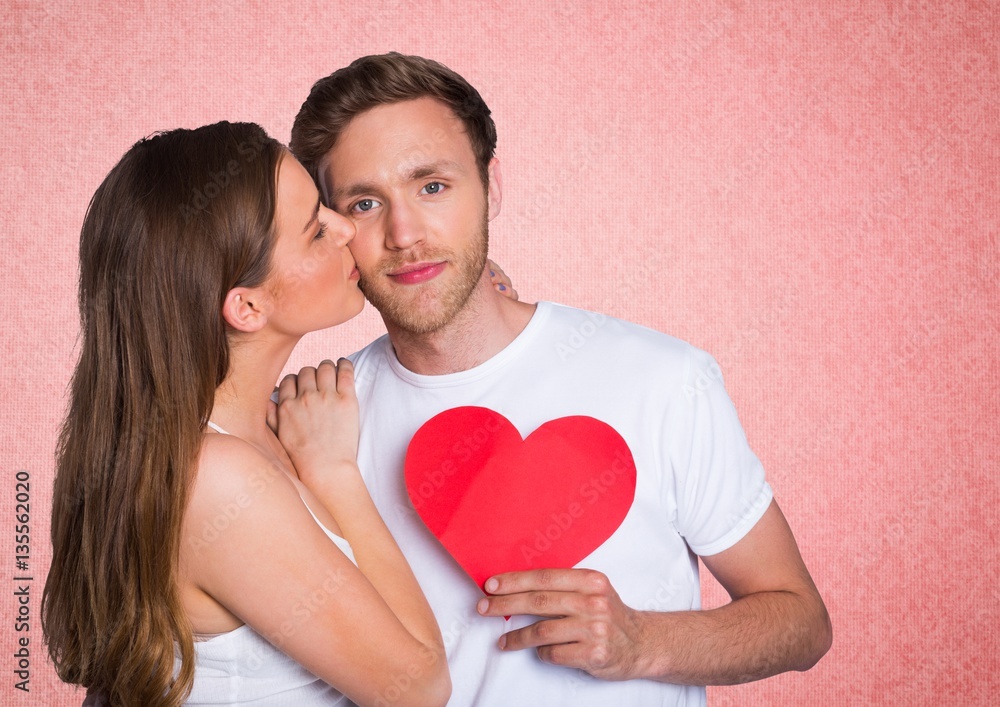 Romantic woman kissing on the cheek of man holding a heart shape