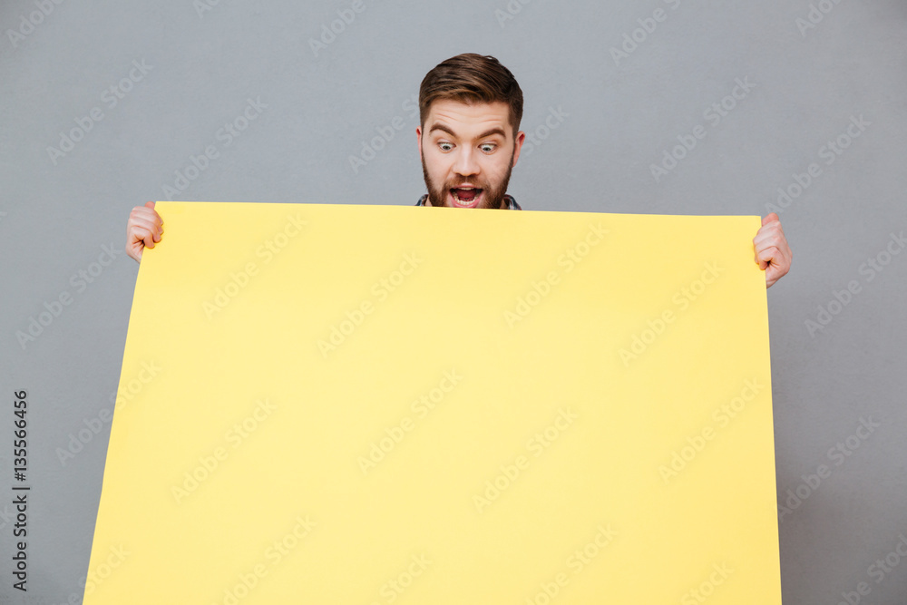 Smiling young bearded man holding copyspace board Smiling young bearded man holding copyspace board