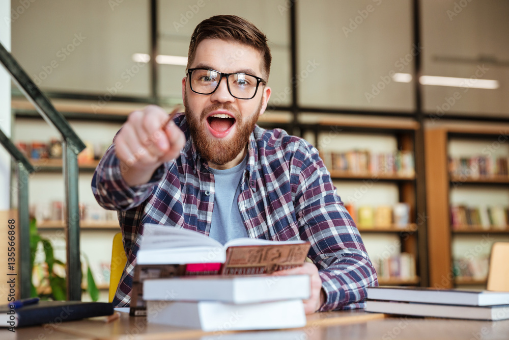 Smiling young student sitting at the desk in library Smiling young student sitting at the desk in library
