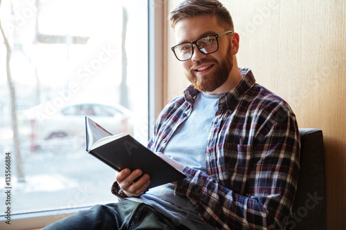 Portrait of a smiling happy male student holding book
