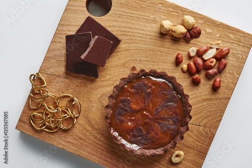 Small Chocolate Tart with huzelnuts and peanut on a white background photo