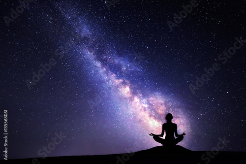 Milky Way and silhouette of a woman practicing yoga.