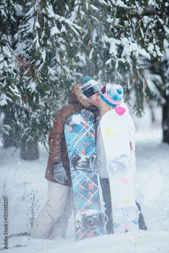 a pair of lovers snowboarders in winter forest