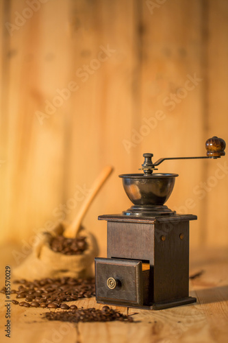 Manual coffee grinder and coffee bean on wooden surface