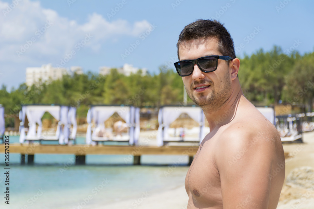 Gym handsome man with nude torso on the beach