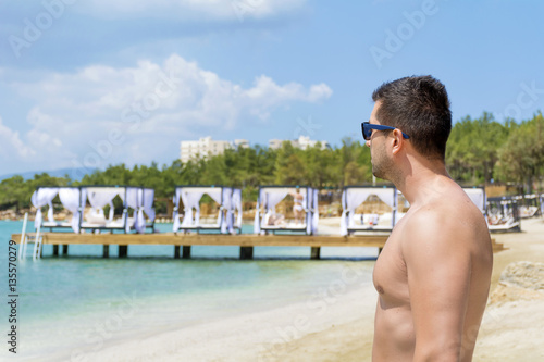 Gym handsome man with nude torso on the beach