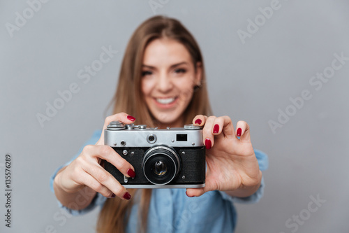 Smiling Woman in shirt making phone on retro camera