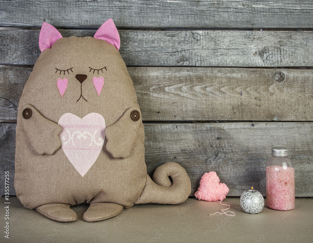 flat wooden background with soft toy cat and pink heats and can