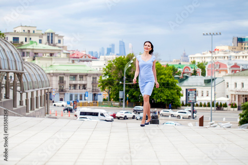 Young beautiful woman in a blue dress walking on the summer stre © Andrey_Arkusha