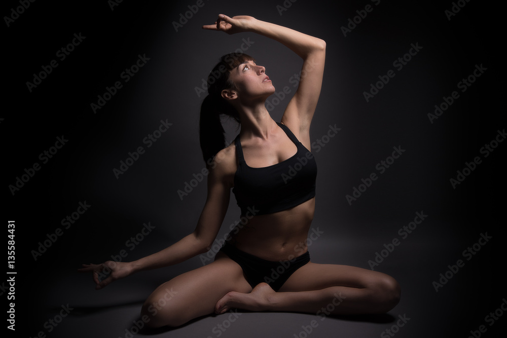 Young fit woman practicing yoga. Healthy lifestyle and sports concept. Isolated on black.