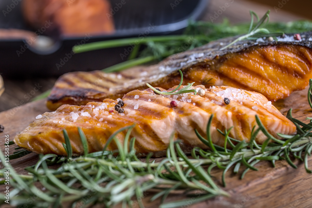 Salmon fillets. Grilled salmon, sesame seeds herb decoration on vintage pan or black slate board. fish roasted on an old wooden table.Studio shot. Salmon fillets. Grilled salmon, sesame seeds herb decoration on vintage pan or black slate board. fish roasted on an old wooden table.Studio shot.