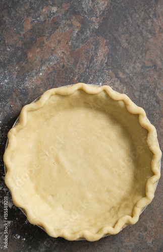 Raw homemade pie crust on a brown stone background. 