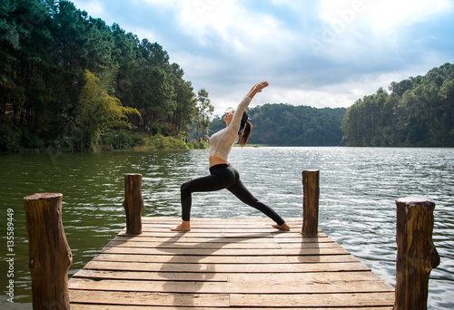 Healthy woman practicing yoga on the bridge in the nature