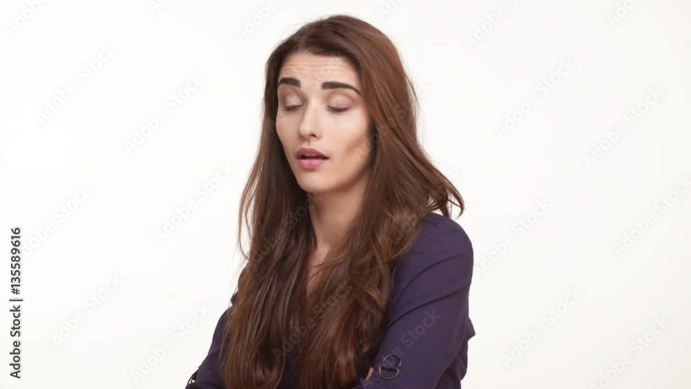 Skeptical young Caucasian female with brown hair wearing dark blue shirt looking forward on white background Skeptical young Caucasian female with brown hair wearing dark blue shirt looking forward on white background