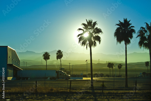 truck unloading and palms in a sunset california landscape.